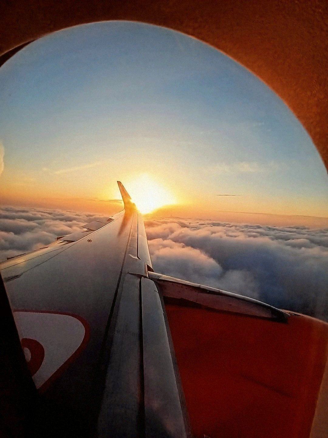 Vista da janela do avião sobre as nuvens ao pôr do sol